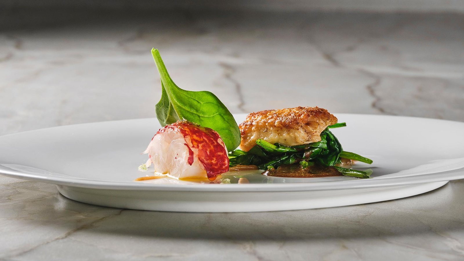 Plato con pescado, mollejas y espinacas salteadas.
